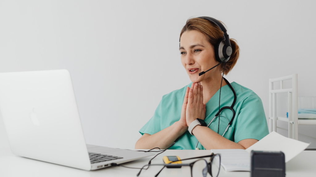 A person sitting at a desk in front of a laptop with headphones on