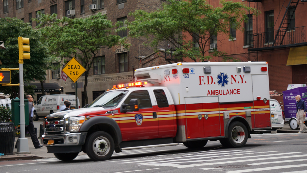 a red and white ambulance driving down a city street