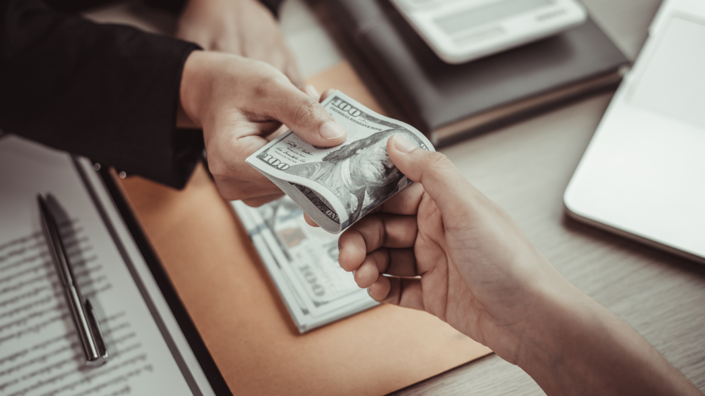 a person handing money to another person at a desk