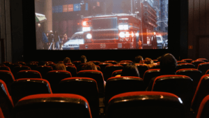 a movie theater with red seats and a fire truck on the screen