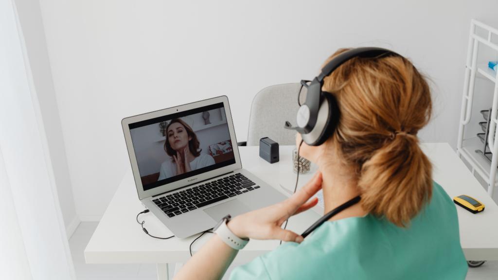 A person sitting at a desk in front of a laptop with headphones on