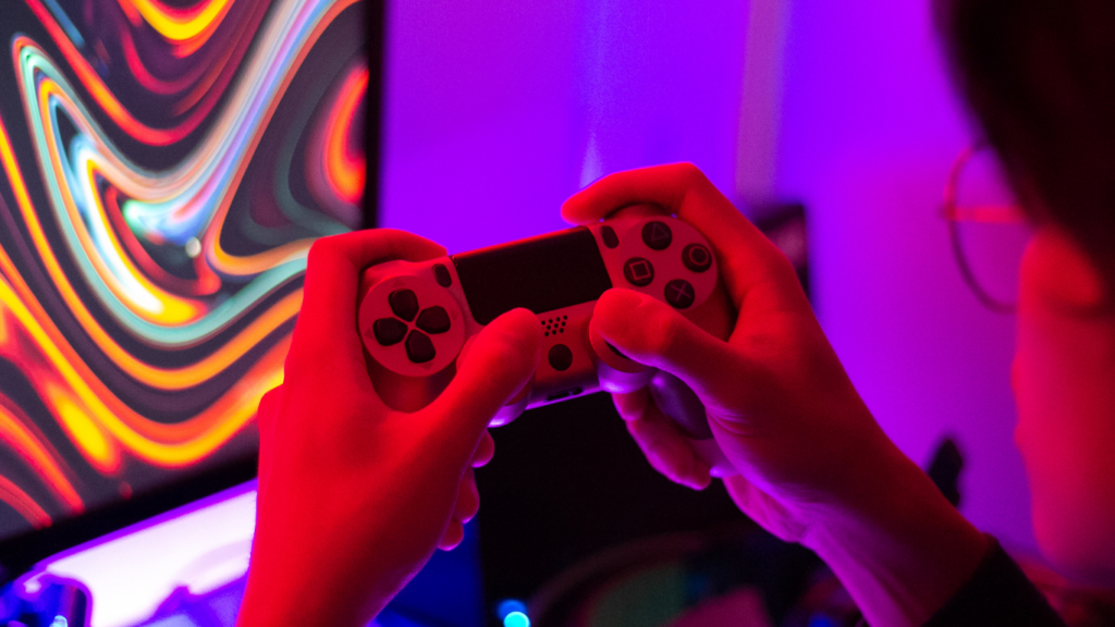 a person holding a video game controller in front of a colorful screen