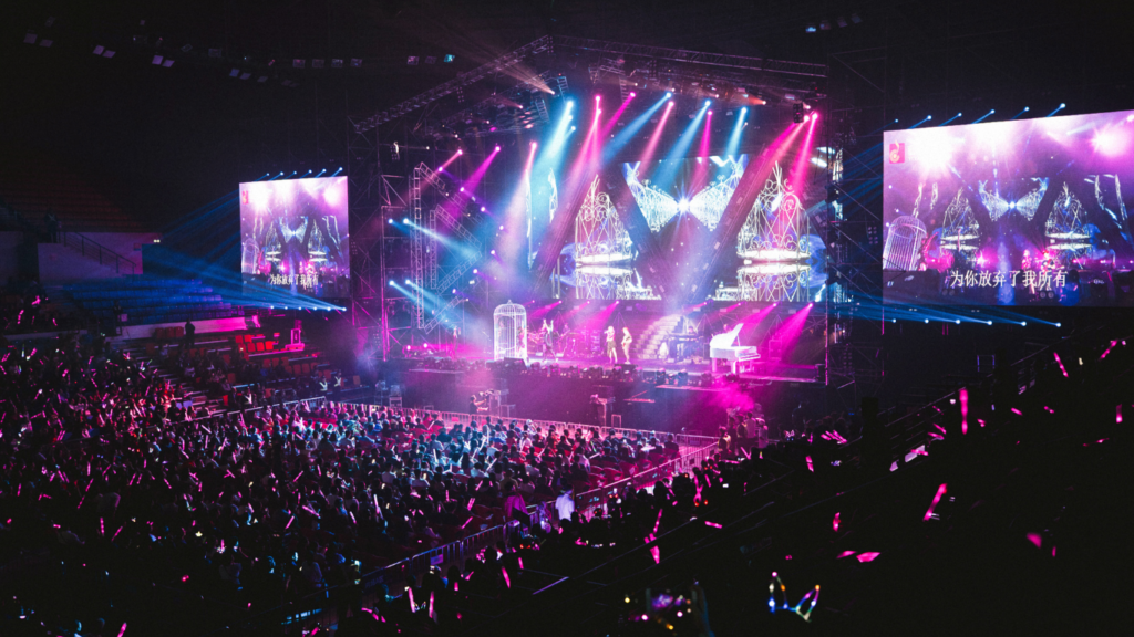 a large crowd at a concert with pink and purple lights