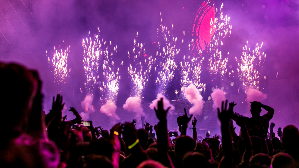 a large crowd at a concert with pink and purple lights