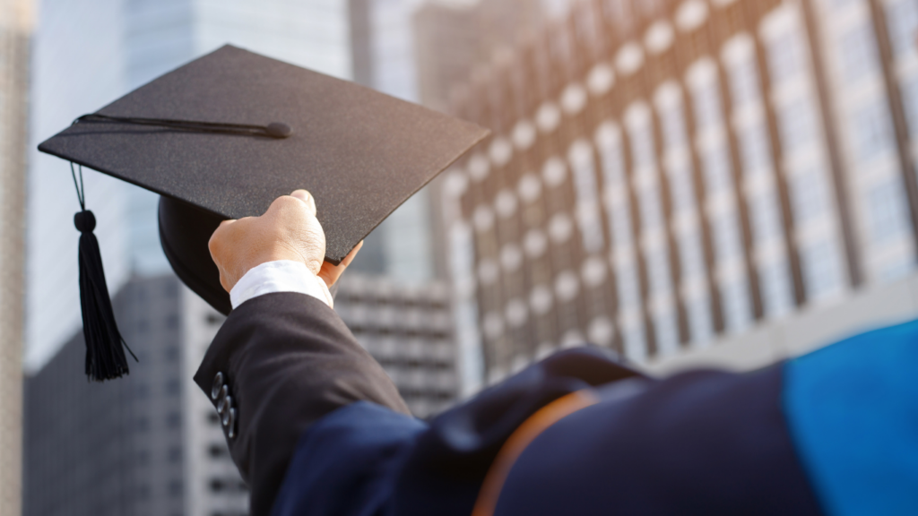 a man in a graduation cap and gown standing in front of tall buildings