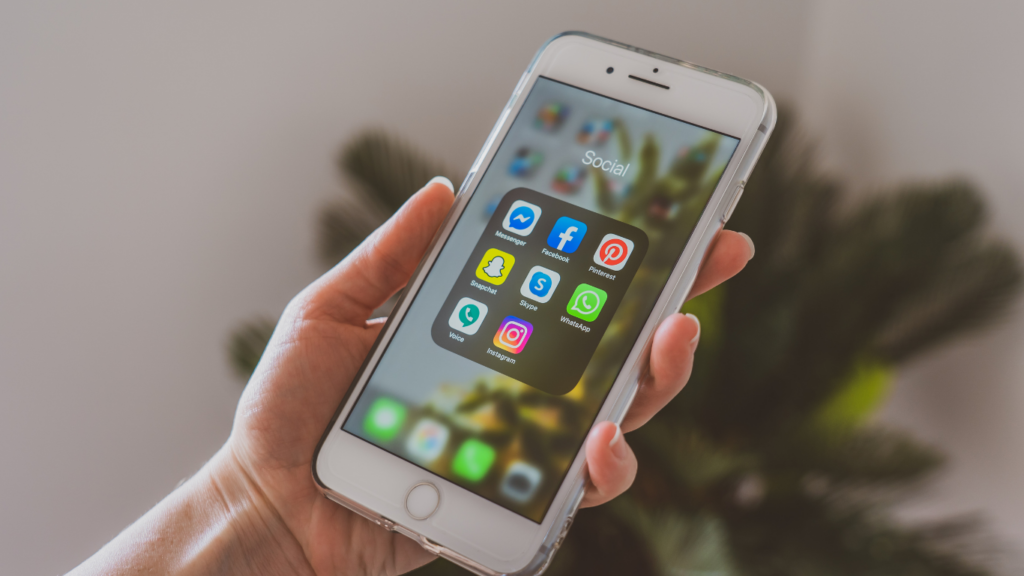 a person holding up a smartphone with various apps on it