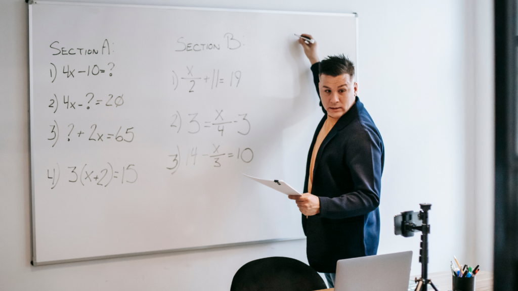 a person is teaching a class in front of a blackboard