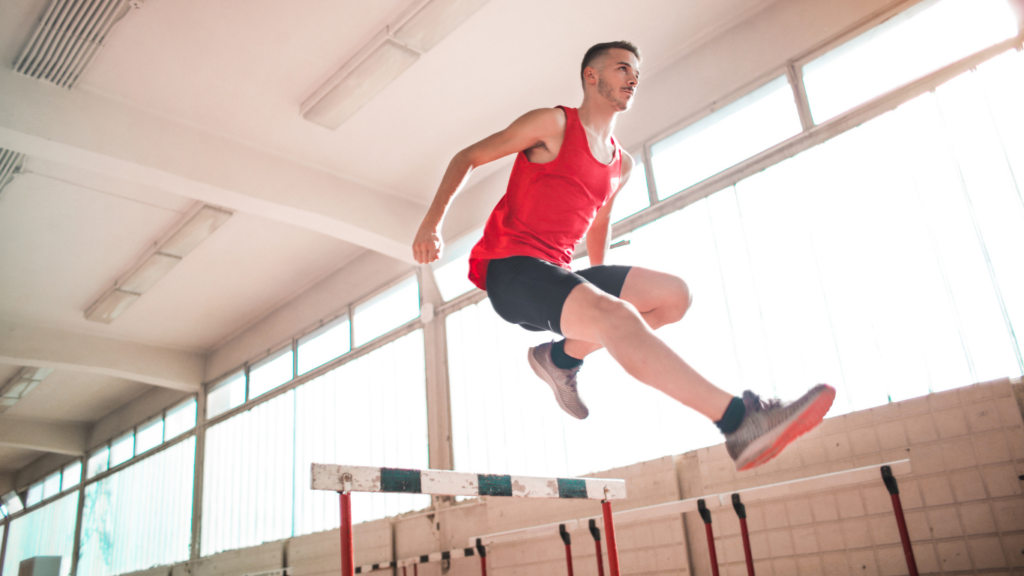 a person jumping over an obstacle in an indoor track