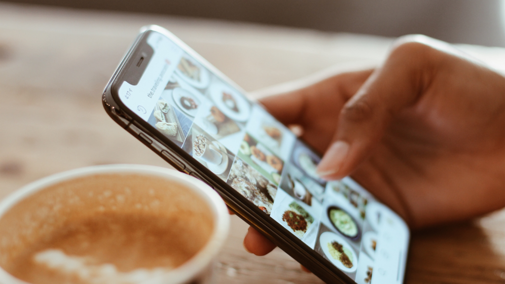 a person using a tablet on a wooden table with a cup of coffee in front of them