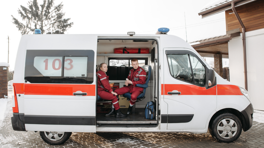 a red and white ambulance driving down a city street